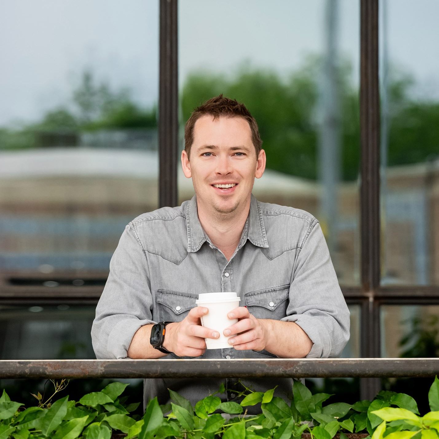 Jon Lofquist at a cafe table with a coffee, smiling at the camera