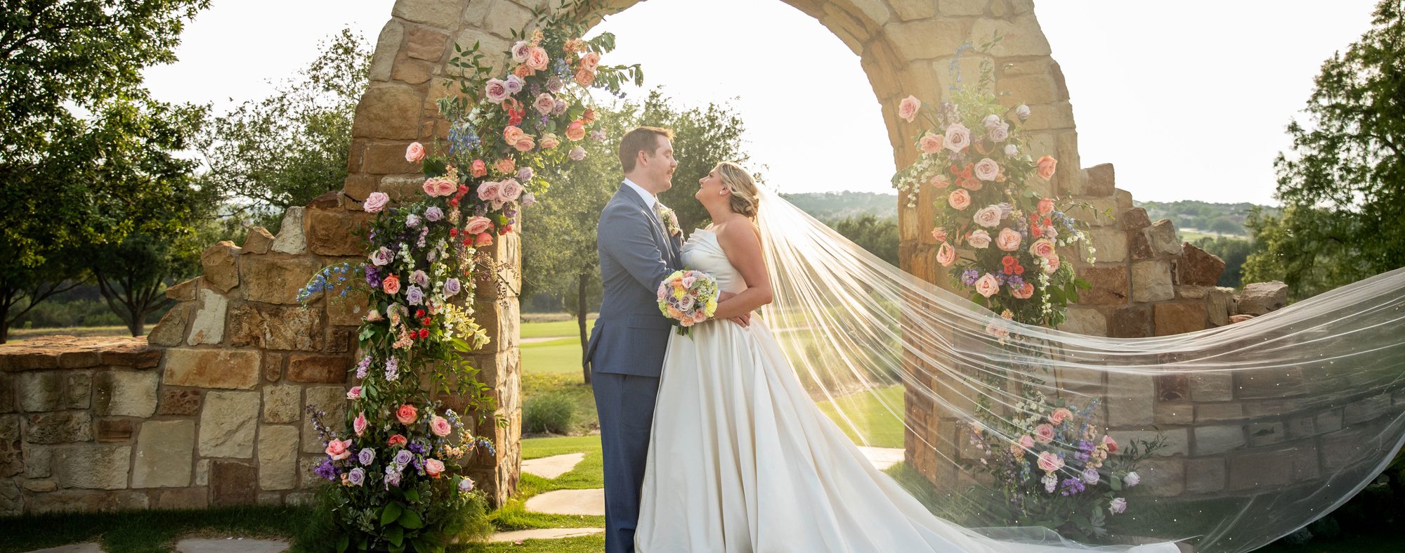 A couple leaning into each other at sunset, the bride's veil catching the last light